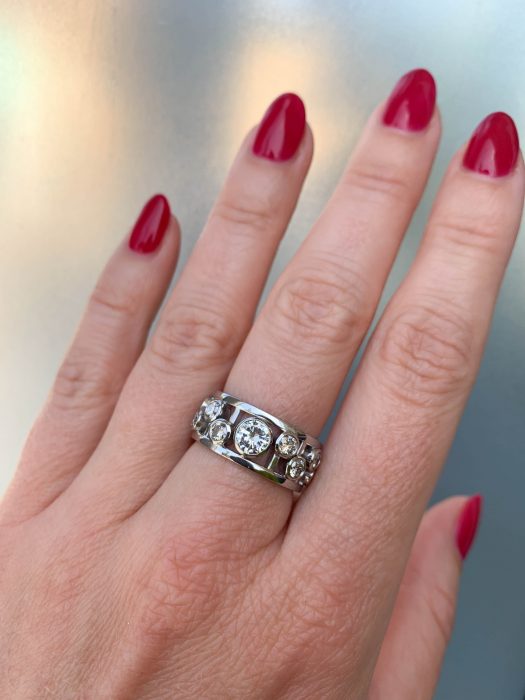 Platinum bespoke ring created by remodelling inherited diamond jewellery into a modern open-frame design - shows worn on hand.
