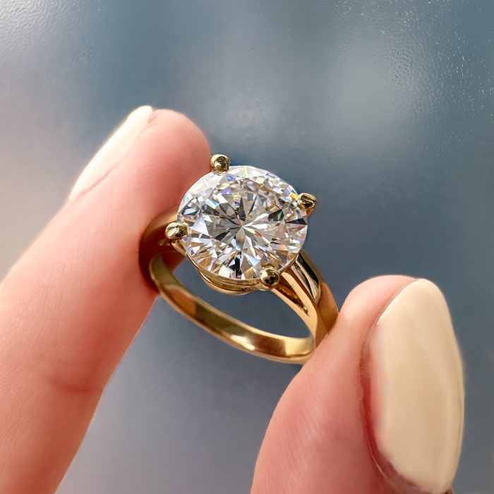 Custom diamond ring being held between two fingers