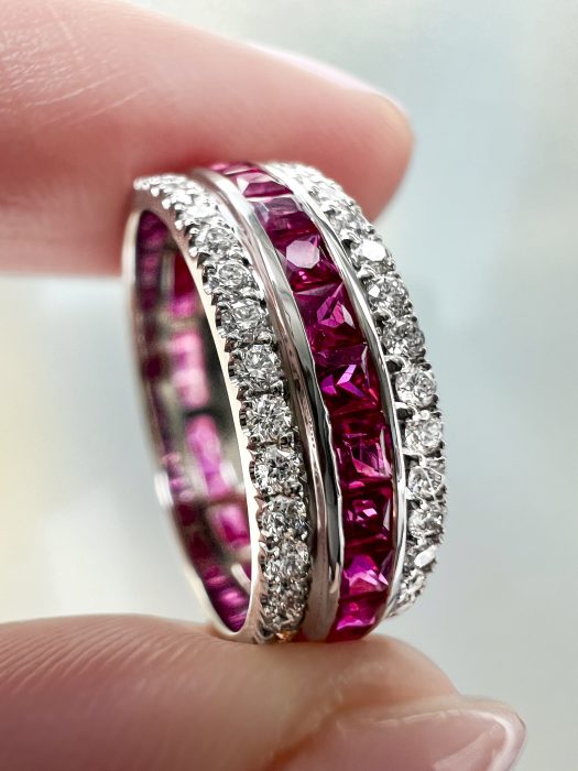 Diamond and ruby custom made wedding ring held between finger and thumb