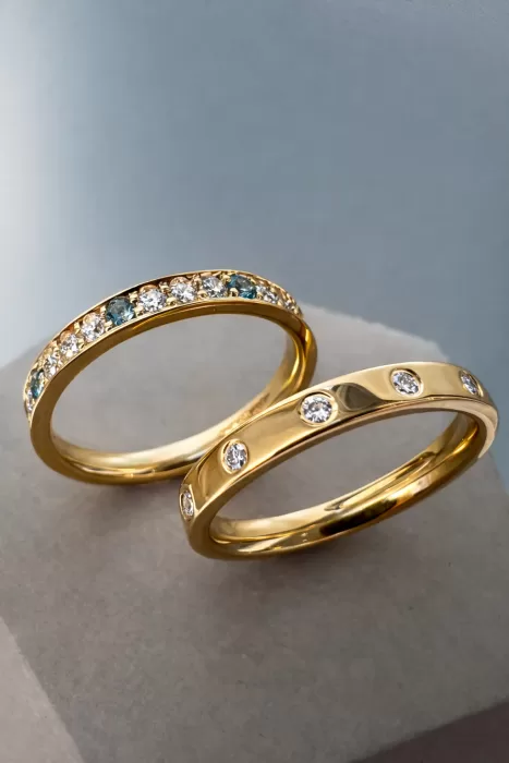 Two Stacking Rings in 18ct Yellow Gold, one flush set with spaced out diamond and one with grain set diamonds, aquamarine and topaz.