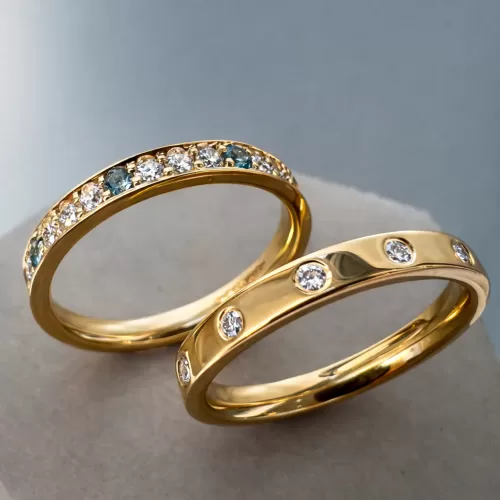 Two Stacking Rings in 18ct Yellow Gold, one flush set with spaced out diamond and one with grain set diamonds, aquamarine and topaz.