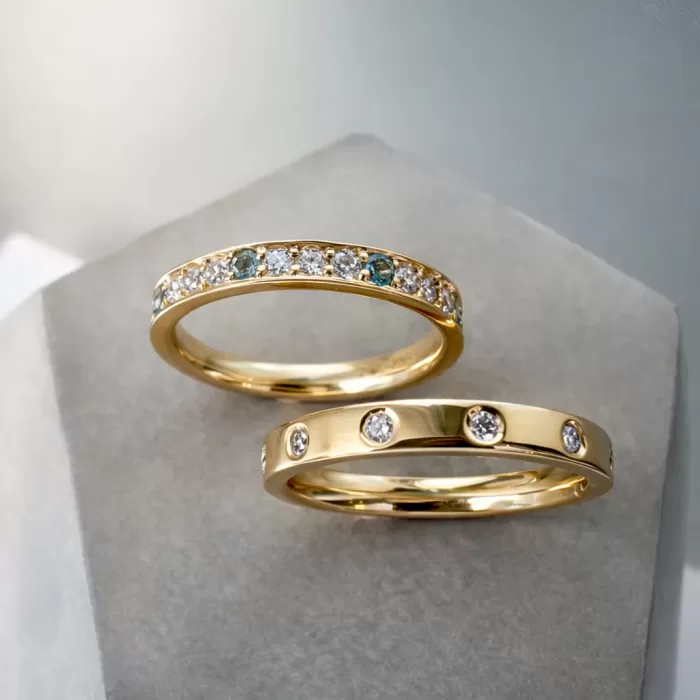 Two Stacking Rings in 18ct Yellow Gold, one flush set with spaced out diamond and one with grain set diamonds, aquamarine and topaz.