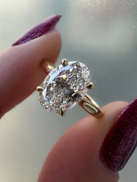 Oval Diamond Custom Engagement Ring held between fingers