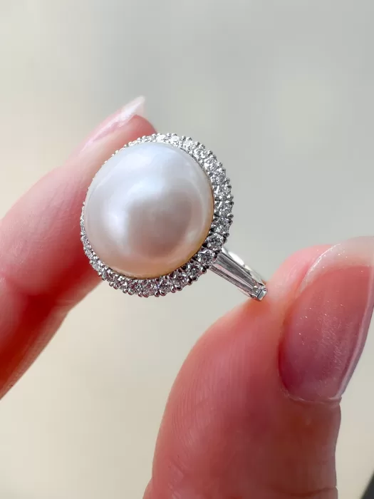 Bespoke Pearl and Diamond Halo Dress Ring held between fingers