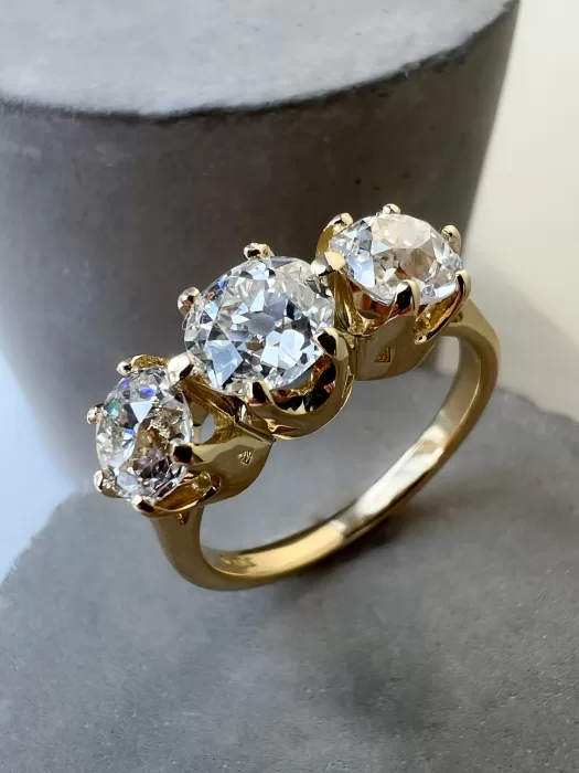Custom Old Cut Diamond Three-Stone Ring with concrete background