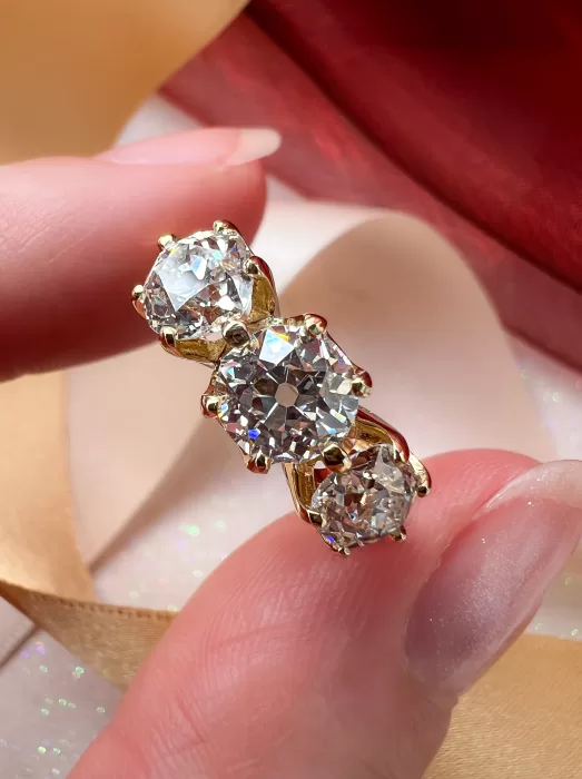 Custom Old Cut Diamond Three-Stone Ring between fingers