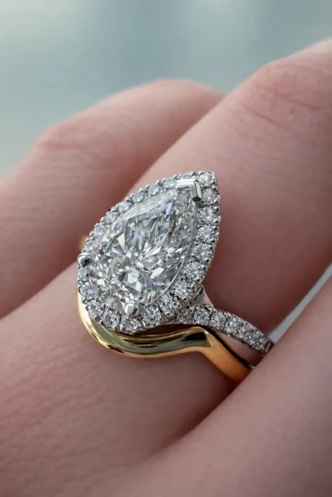 Custom Pear Cut Diamond Halo Engagement Ring on hand with gold wedding ring