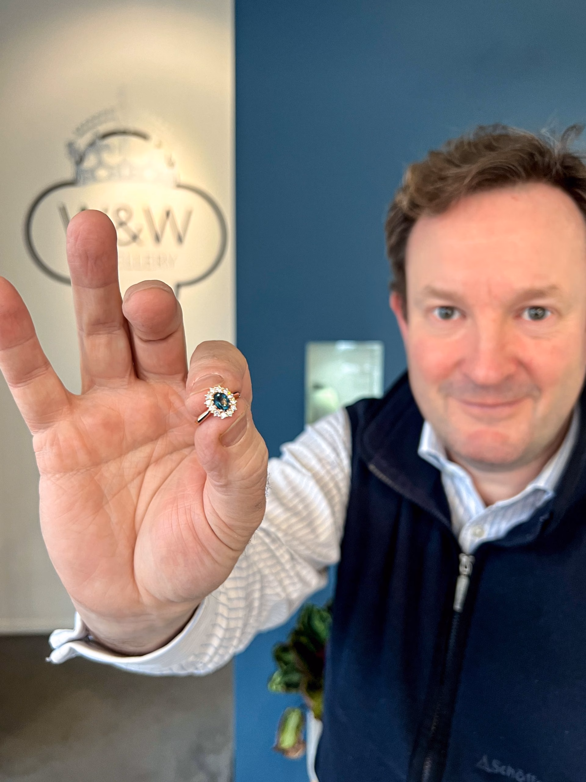 Richard with Ring teal sapphire vintage bespoke engagement ring being held by designer
