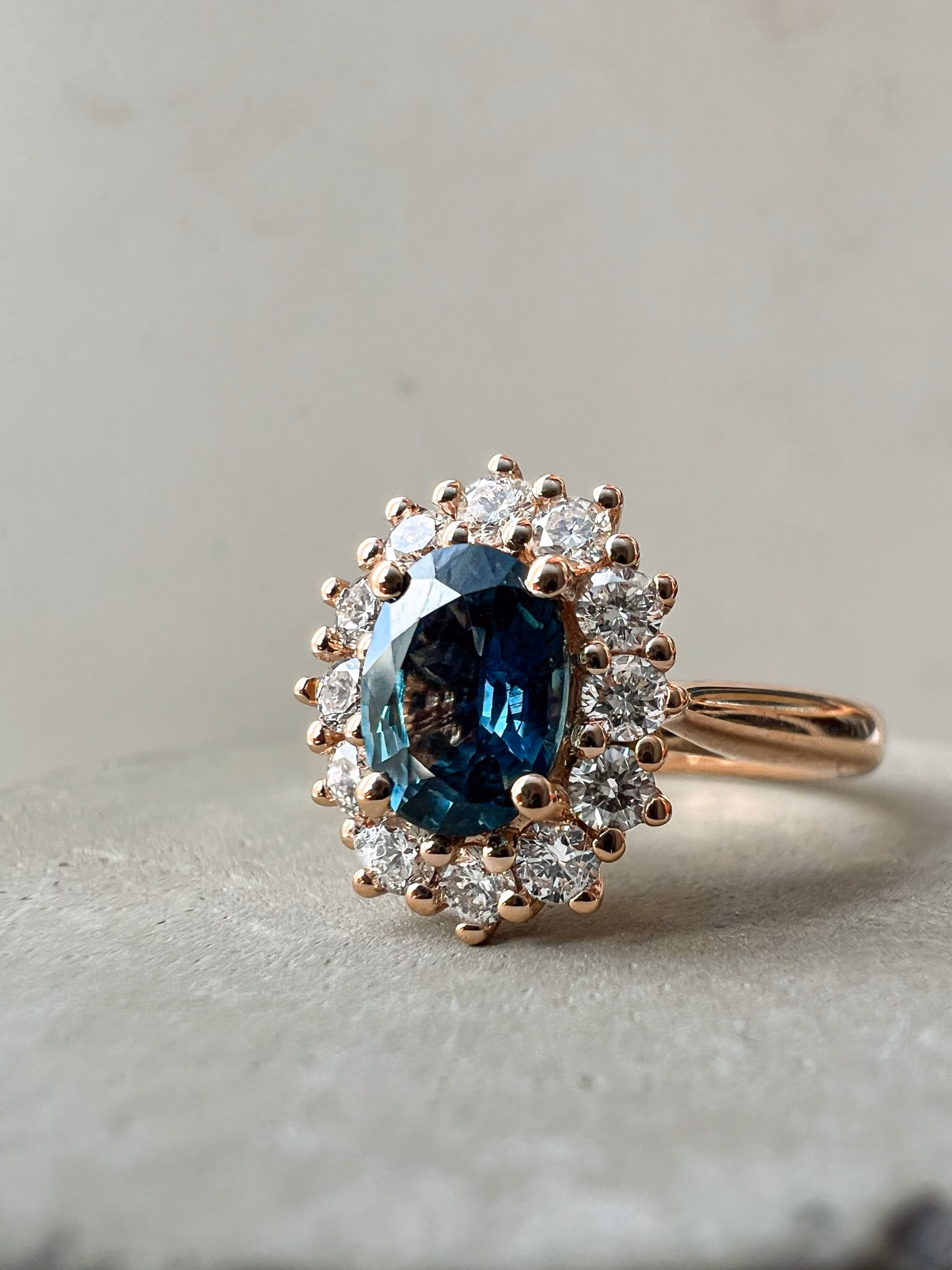 Ring concrete teal sapphire vintage bespoke engagement ring against stone background