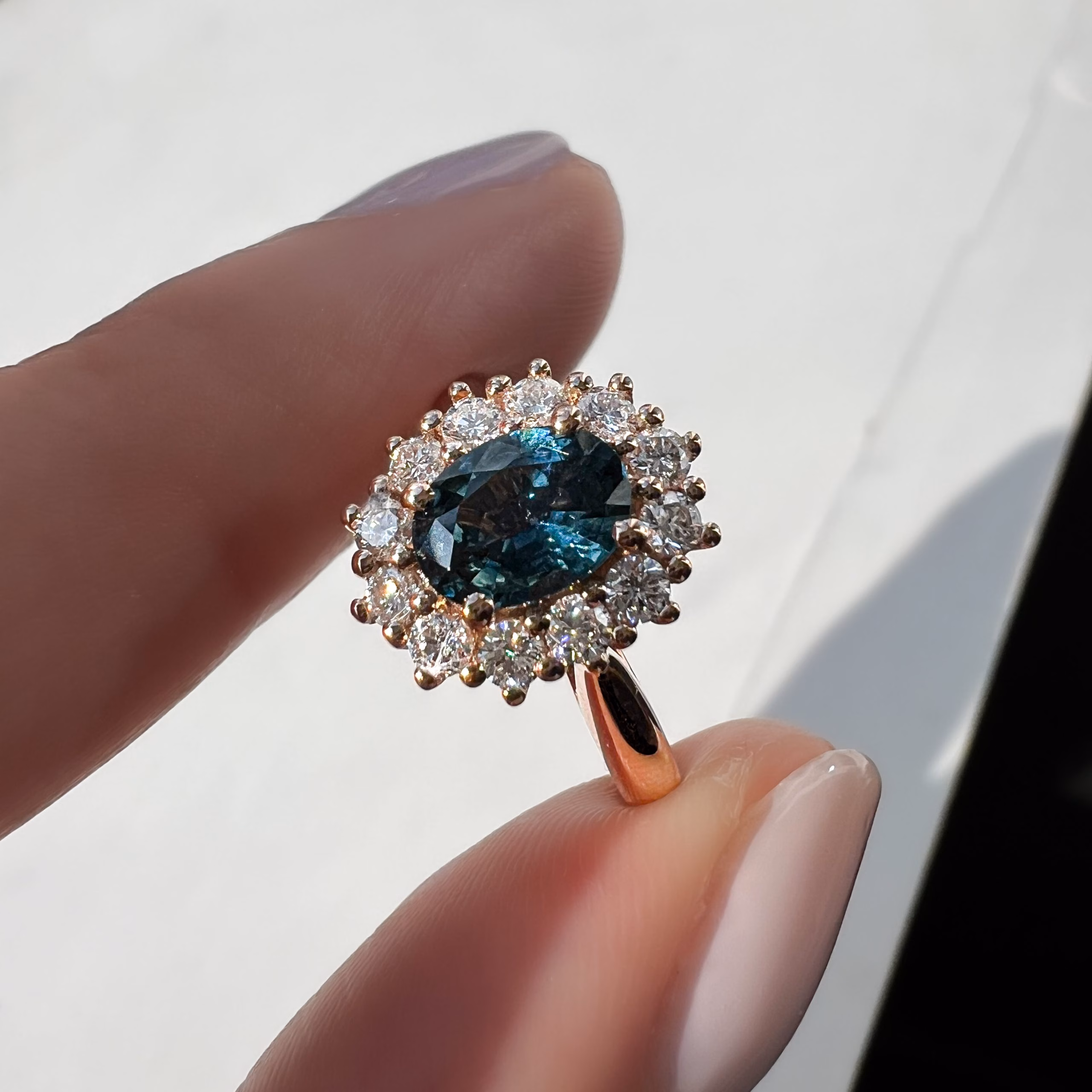 Ring Front Sun Fingers teal sapphire vintage bespoke engagement ring held between finger and thumb